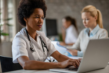 Female African American doctor working on laptop in the office.