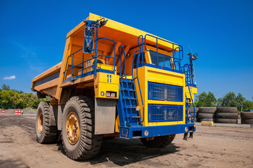 heavy yellow quarry dump truck at repair station at sunny cloudless day