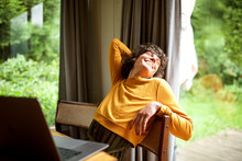 Woman Relaxing At Home Looking Out Of Window