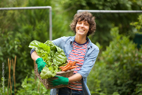 Fotografía female farmer smiling with bunch of vegetables in basket