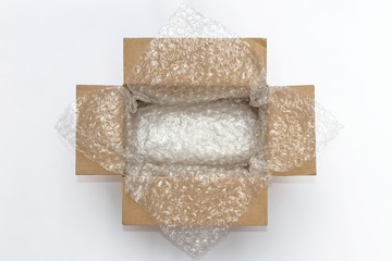 Plastic air bubble wrapped items in a brown parcel cardboard box, ready to be shipped.