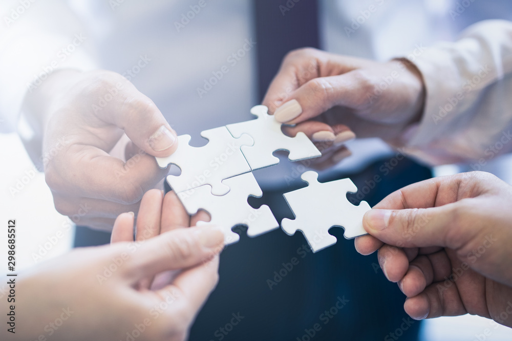 A group of business people assembling jigsaw puzzle. - obrazy, fototapety, plakaty 
