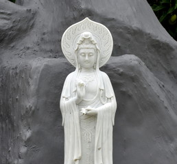 Wall Mural - White Buddha statue in front of a rock in front of a Chinese temple