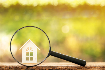 Magnifying glass with home model put on the wood on bokeh background, Loan for real estate and searching for buy a new house to family in the future concept.