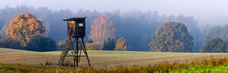 Hunting tower on the edge of the forest during a beautiful sunrise on a foggy morning