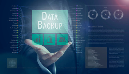 Businessman outreached hand holding a Data Backup business concept on a computerised screen display.