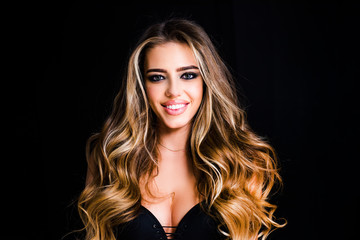 Wall Mural - Beautiful woman with long smooth shiny straight hair. Blond woman with long curly beautiful hair. Close up beauty portrait of a laughing beautiful woman on black background.