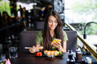 © F8  \ Suport Ukraine - Young woman texting on the phone while eating sushi in a restaurant