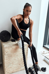 Wall Mural - young attractive female with perfect body in sportswear holding rope. have rest after training