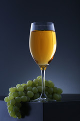 Wall Mural - Glass of white wine with grape on black table