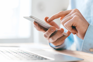 Aufkleber - Hands of young businessman pointing at smartphone screen over laptop keypad