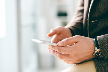 Aufkleber - Young elegant businessman with wristwatch holding smartphone while texting