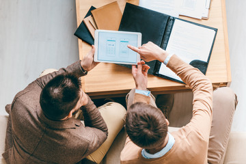 Aufkleber - Top view of two young businessmen discussing new software for smartphones