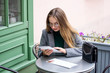 © ostapenkonat - Young beautiful blonde in glasses sits in a cafe on the street and in the inside.