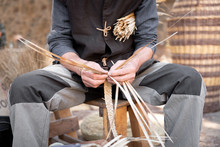 Old Wicker Craftsman With Hands Working In Isolated Foreground.