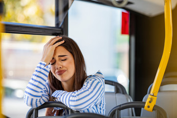 Worried young woman traveling inside of a bus. Beautiful sad woman traveling with bus, hands on head. Pensive woman traveling with public transport. Worried young woman traveling inside of a bus