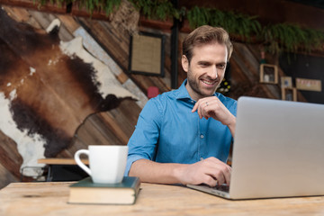 Wall Mural - Cheerful casual man laughing and reading from his laptop