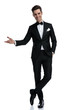 © Viorel Sima - smiling elegant man in tuxedo inviting and presenting to side