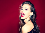 Tongue and sexy mouth. Beauty face of the young beautiful woman - isolated on white. Studio fashion shot. Face of a beautiful girl with smoky eyes makeup posing at studio over dark background.