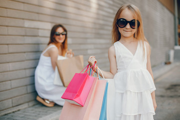 Beautiful girl in a summer city. Lady with shopping bags. Mother with daughter in stylish clothes