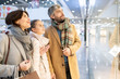 © pressmaster - Young family standing by shop window and discussing new collection of casualwear