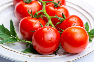 Bunch of fresh ripe red tomatoes with leaves on board and  white background