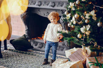 Sticker - Cute little boy in a white sweater. Child by the christmas tree