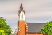 Side View Of Church Exterior With Focus On Steeple And Roof Against Cloudy Sky