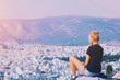 © raisondtre - Young tourist woman sitting on top of mountain and looking at a beautiful landscape cityscape Athens Greece. Adult girl tourist relax on hill overlooking Athens in summer. Famous Athens city in Europe