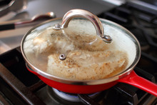 Chicken Breasts Cooking In An Enameled Cast Iron Skillet On The Stovetop In A Home Kitchen.
