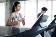 Young people running on a treadmill in gym.