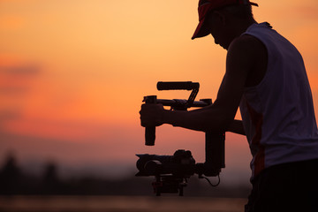 The black silhouette of a video photographer was filmed with a camera and stabilized like a pro.