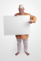 Wall Mural - Bald man holding a white blank sign board standing over white background in traditional Indian Kurta Pyjamas with Ghandi Topi (Cap).