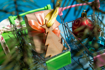 Wall Mural - Colorful gift boxes fir, spruce, branches in shopping cart on a wooden blue background. The concept of preparing for the holidays New Year and Christmas.