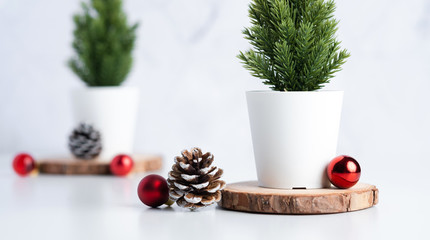 Poster - christmas tree with pine cone and decor xmas ball on white table and marble tile wall background.clean minimal simple style.holiday still life