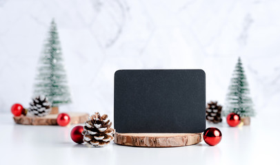 Poster - blackboard with christmas tree with pine cone and decor xmas ball on white table and marble tile wall background.clean minimal simple style.holiday still life mock up banner with space to adding text