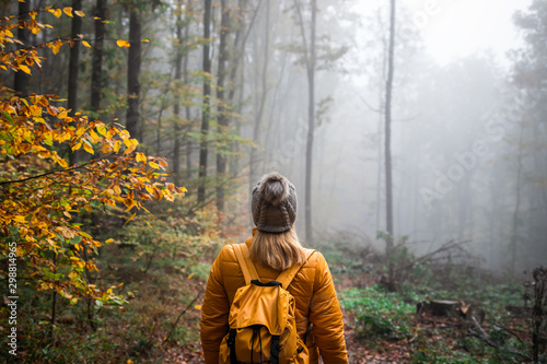 Fotomural Woman with knit hat and backpack hiking in foggy woodland