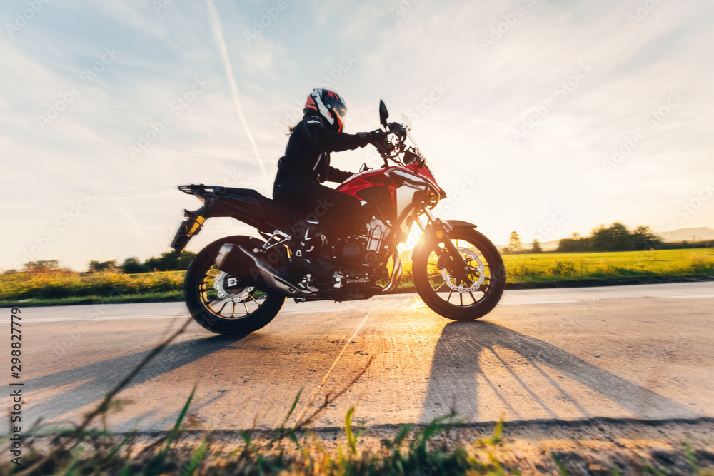 Fast motorcycle drive on asphalt road at sunset. - obrazy, fototapety, plakaty 