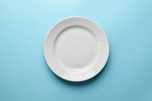 Empty Plate On Blue Background, Copy Space. Restaurant Business Went Broke Concept. Visitor Of An Luxury Restaurant Is Waiting For An Order.