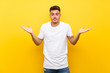 © luismolinero - Young handsome man over isolated yellow background making doubts gesture