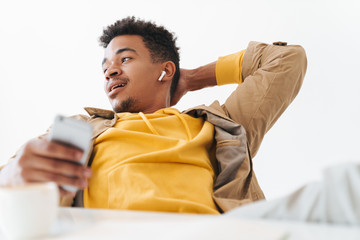 Sticker - Image of african american guy using smartphone and earbuds in of