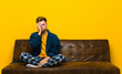 © kues1 - young man wearing pajamas feeling bored, frustrated and sleepy after a tiresome, dull and tedious task, holding face with hand . sitting on a sofa