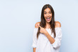 © luismolinero - Young woman over isolated blue background pointing finger to the side