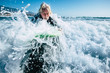 © Daniel - senior trying to surf a wave on the sea at the beach alone with black wetsuit and green surftable - vacation at the sea and active retired man