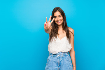 young woman over isolated blue background happy and counting three with fingers