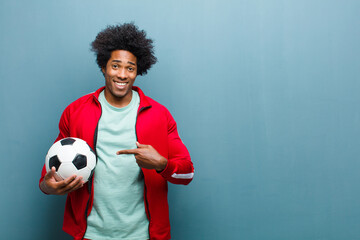 young black sports man with a soccer ball against blue grunge wa