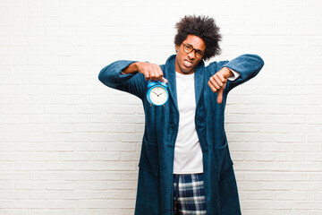 Wall Mural - young black man wearing pajamas with an alarm clock