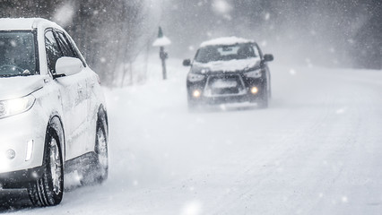 Wall Mural - Winter road in beatiful forest. Snow calamity or blizzard. Fast cars on snowy roads in storm.