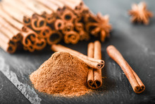 Cinnamon Sticks Spices On Dark Stone Table. Cinnamons Milled Powder In White Bowl On Black Board.