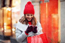 Beautiful Woman Using Mobile Phone During Shopping In Wintertime